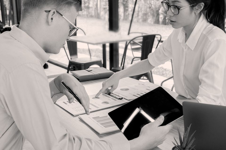 Two colleagues reviewing data together, in black and white